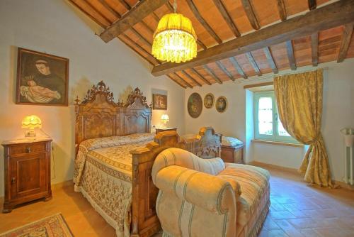 a bedroom with a large wooden bed and a chair at Casale San Martino by PosarelliVillas in Cortona