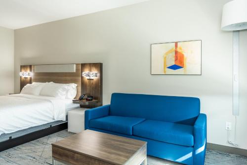 a hotel room with a bed and a blue couch at Holiday Inn Express & Suites Charlottesville by IHG in Charlottesville