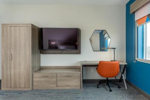 an office with a desk with a tv and a chair at Holiday Inn Express & Suites Charlottesville by IHG in Charlottesville