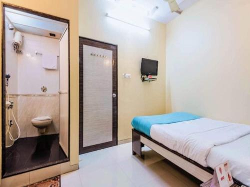 a bedroom with a bed and a bathroom with a shower at Hotel Broadway Colaba in Mumbai