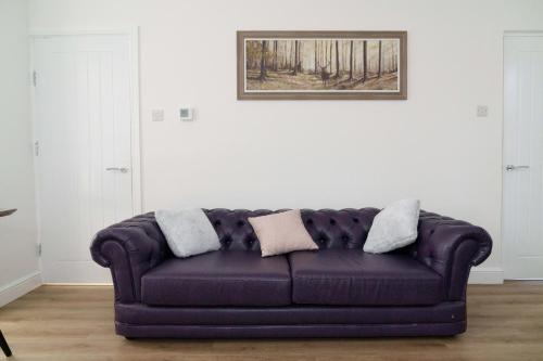 a purple couch in a living room with a picture on the wall at Nowell House in Leeds
