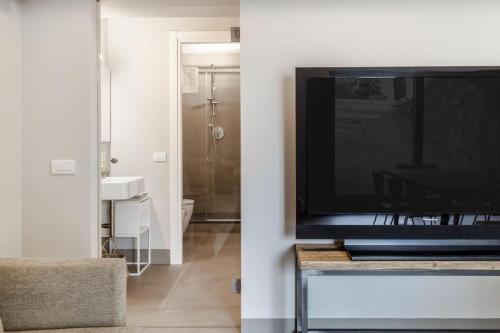 een woonkamer met een televisie en een badkamer bij Villa Chiugi by PosarelliVillas in Seggiano