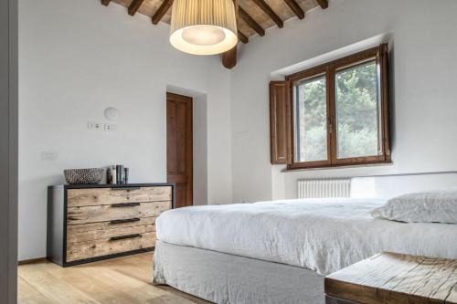 een witte slaapkamer met een bed en een raam bij Villa Chiugi by PosarelliVillas in Seggiano