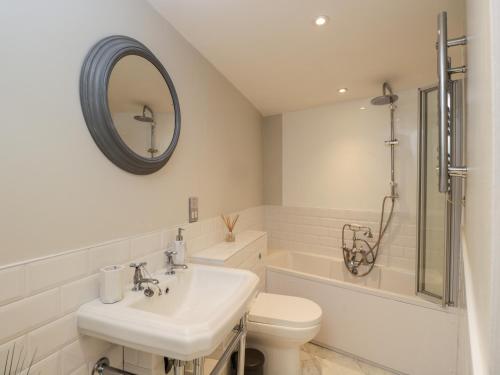 Un baño con lavabo, inodoro y espejo. en Stable Cottage, en Cheltenham