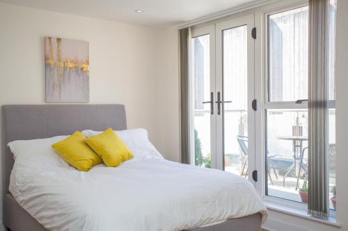 Un dormitorio con una cama con almohadas amarillas y una ventana en Gorgeous Central Studio with Balcony, 2 mins to Beach and Pier, en Worthing