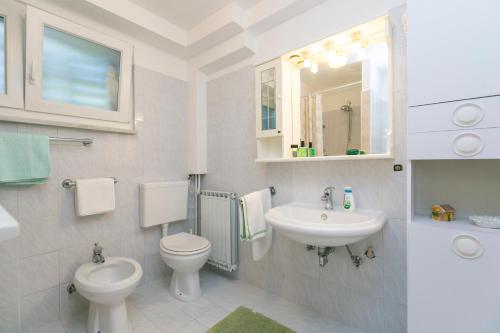 a white bathroom with a sink and a toilet at Apartman Vito in Labin