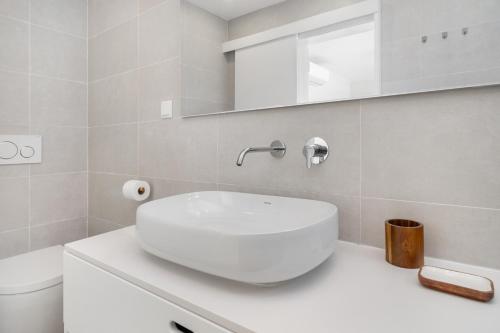 a white bathroom with a sink and a toilet at Villa do Pinhal in Olhos de Água