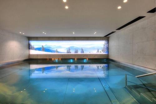 - une grande piscine avec un grand écran dans un bâtiment dans l'établissement Très bel appartement avec Spa à Megeve Stallion D 25, à Megève