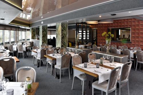 a restaurant with tables and chairs in a room at Hôtel du Lac in Butgenbach