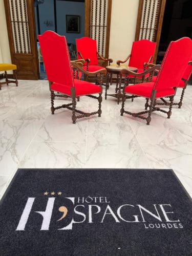 a group of red chairs and a rug on a floor at Grand Hôtel d'Espagne in Lourdes