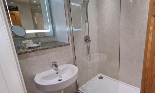 a bathroom with a white sink and a shower at Biggin Hall Country House Hotel in Hartington