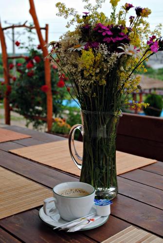 a vase of flowers and a cup of coffee on a table at Pensiunea Faur in Sebeş