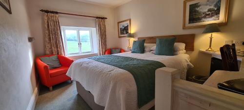 a bedroom with a bed and a red chair at Biggin Hall Country House Hotel in Hartington