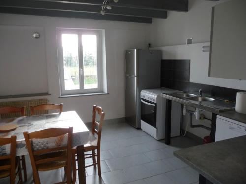 a kitchen with a table and a refrigerator at Gîte des Forces - Limousin - Haute Vienne in Saint-Bazile