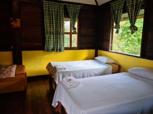 San MiguelにあるLos Gallitos Eco Lodgeのベッド2台と窓が備わる客室です。