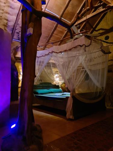 a bed with a canopy in a room with a tree at Humbhaha jungle nature eco resort in Kataragama