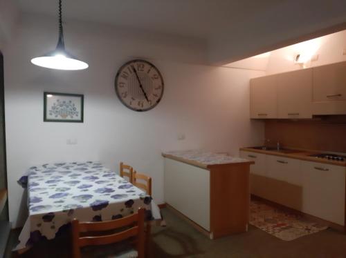 a kitchen with a clock on the wall and a table at Appartamenti Vacanze Casa -Residence Albare - check in Vacanze Casa - Marilleva 900 in Marilleva