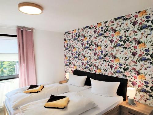 1 dormitorio con 2 camas y papel pintado con motivos florales en Pfefferstübchen Ferienwohnung Schanzenblick, en Brotterode