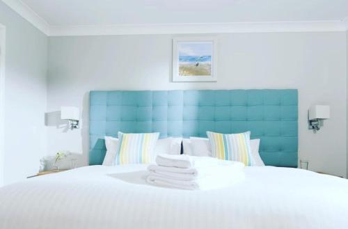 a bedroom with a white bed with a blue headboard at Padstow 2 bedroom Lodge at Retallack Resort in Padstow