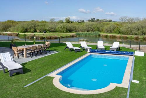 a swimming pool with chairs and a table and a table and chairsitures at Herons House Sleeps 12, heated Pool, hot tub, sauna, games room 5 Star! in Saint Columb Major