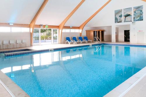 a large swimming pool with blue chairs in a building at Herons House Sleeps 12, heated Pool, hot tub, sauna, games room 5 Star! in Saint Columb Major