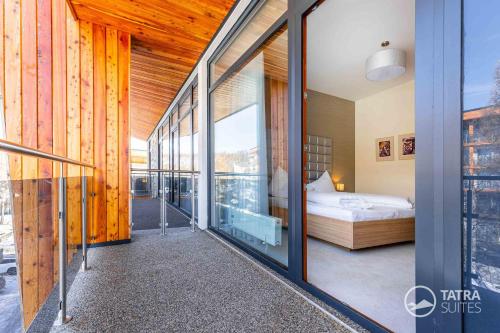 - une chambre avec un lit et un balcon dans l'établissement TATRA SUITES Senior Lux Apartment C413, à Starý Smokovec
