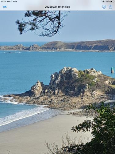 an island in the ocean with a sandy beach at Le studio de la plage in Perros-Guirec