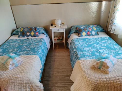 a bedroom with two beds and a table with a night stand at Las Cigüeñas de San Cristóbal in San Cristóbal de Segovia