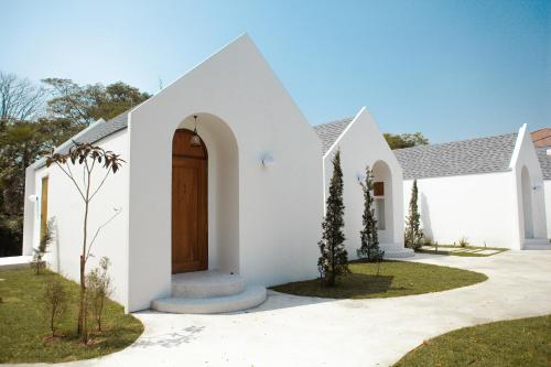 a white house with a brown door at La Kana Boutique Villa in Kamphaeng Phet