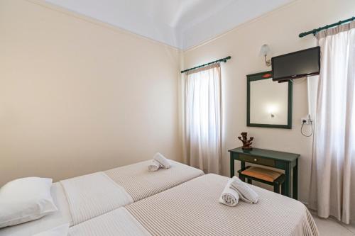 two beds in a room with a mirror and a desk at Gianna Apartments in Almirida