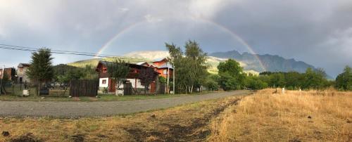 a rainbow in the sky over a house and a road at El Bolsón Patagonia - Cabaña Tío Ale in El Bolsón