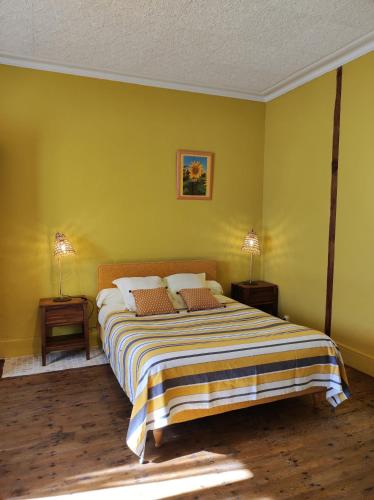 - une chambre avec un grand lit aux murs jaunes dans l'établissement Chez Nathalie Et Jean Claude, à Saint-Marc-à-Frongier