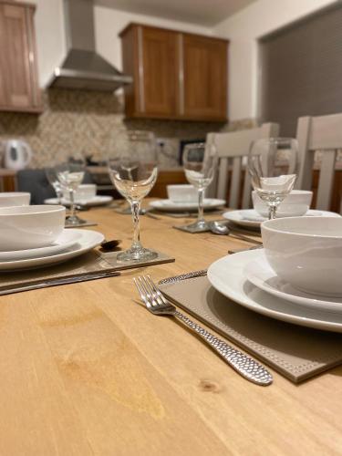 a wooden table with plates and wine glasses on it at Cheerful home near City Centre,Station& RaceCourse in Doncaster
