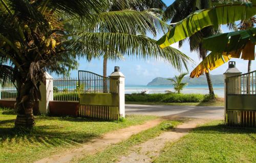 a gate with a palm tree in front of the ocean at HideAway in Anse Possession