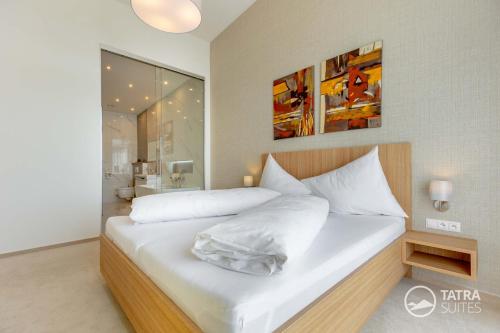 a bedroom with a large white bed and a bathroom at TATRA SUITES Senior Lux Apartment C413 in Smokovce