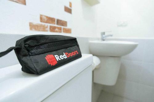 una bolsa negra en la parte superior de un mostrador del baño en RedDoorz near Mall Ratu Indah 3, en Balangberu