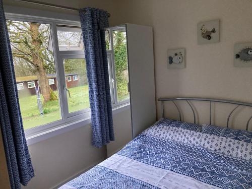 a bedroom with a bed and two windows at 13 The Park in Kilkhampton