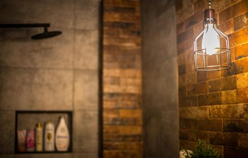 aendant light hanging from a brick wall with bottles of wine at The Old Market House in Tríkala