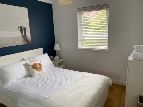 Un dormitorio con una cama blanca con un gato sobre una almohada en Edinburgh Seaside Apartment en Edimburgo