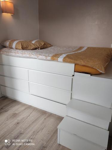 a bed with white drawers in a bedroom at Apt lumineux in Gonesse