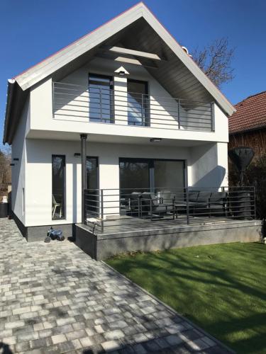 a white house with a porch and a patio at Napsugár Vendégház in Zánka