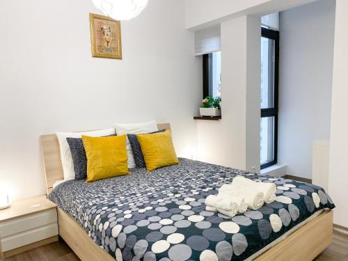 um quarto com uma cama com almofadas amarelas e brancas em VR2 Central Apartment em Bucareste