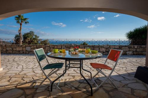 a patio with a table and chairs with a view of the ocean at Vivian's Studio Endless View in Svoronata