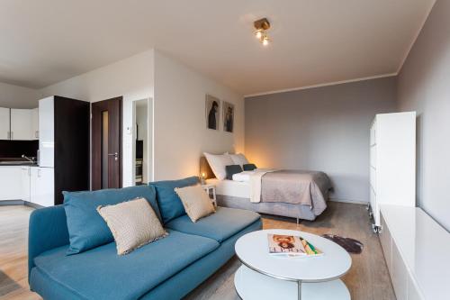 sala de estar con sofá azul y cama en Golden Apartments Rezidence Nová Karolina II., en Ostrava