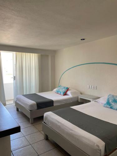 a hotel room with two beds and a window at Luna Creciente in Santa Cruz Huatulco