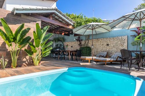 uma piscina com um pátio com uma mesa e cadeiras em CASA CAJU em Aracaju