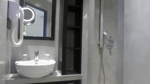 a bathroom with a sink and a shower with a mirror at Logis Hôtel Saint Guirec Et De La Plage in Perros-Guirec