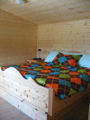 a bed in a wooden cabin with a colorful comforter at Tschurtschenthaler Rentals in Golden