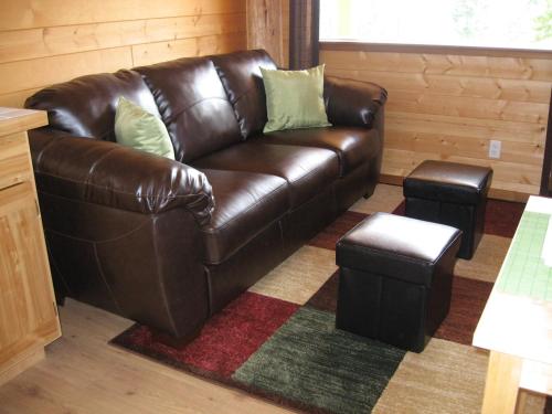 sofá de cuero marrón y taburete en la sala de estar en Tschurtschenthaler Rentals en Golden