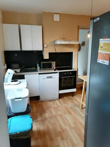 une cuisine avec des armoires blanches et un four à plaques de cuisson dans l'établissement Villa des Roses - Maison familiale, 3 chambres au calme, wifi, au Havre